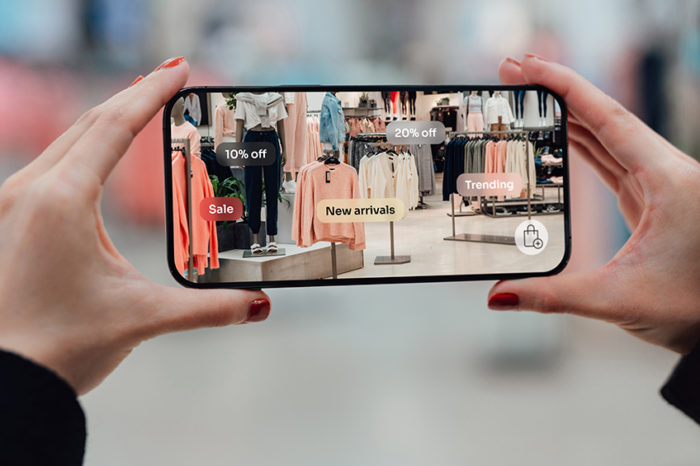 A shopper uses an augmented reality app on a mobile phone to view clothing offers in a retail store.