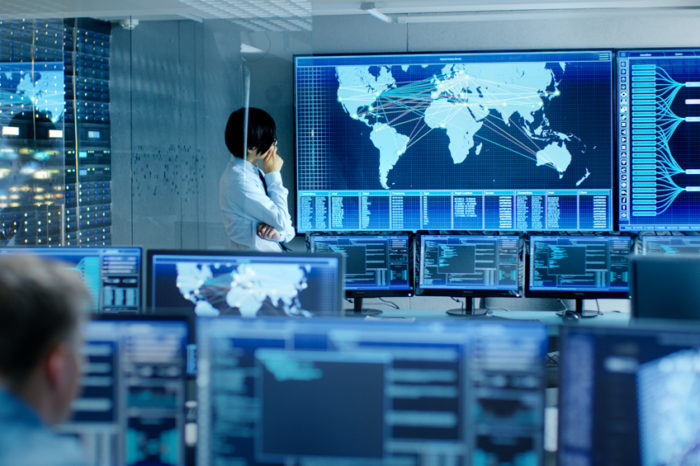 Businessman in control center looking at world map on screen