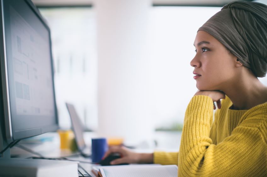 Woman sitting at a desk, looking at a computer screen.