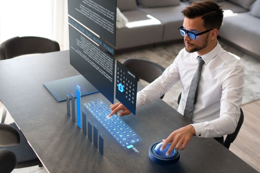Image of a man at a desk looking at a virtual screen and keyboard.