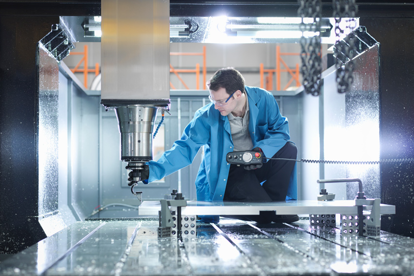 Man in manufacturing space inspecting equipment.