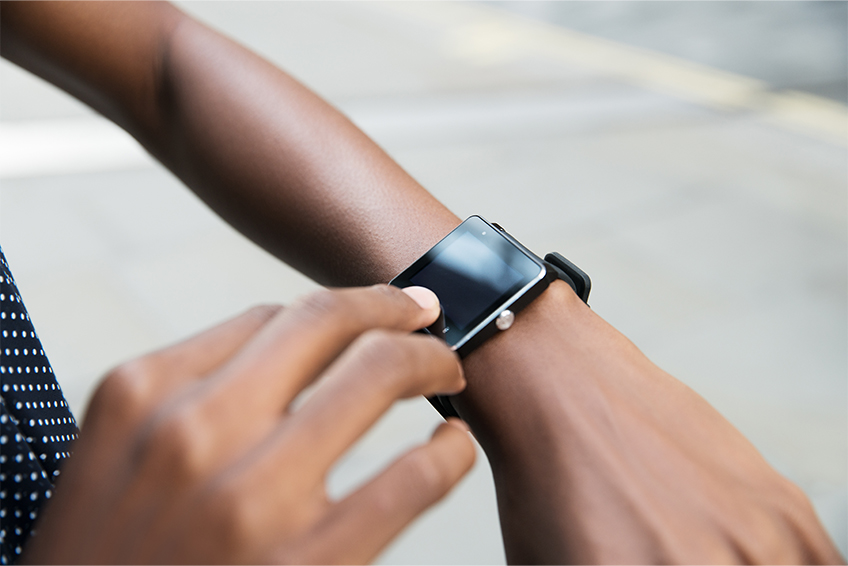 Image of a persons arm and hands while they look at a smart watch
