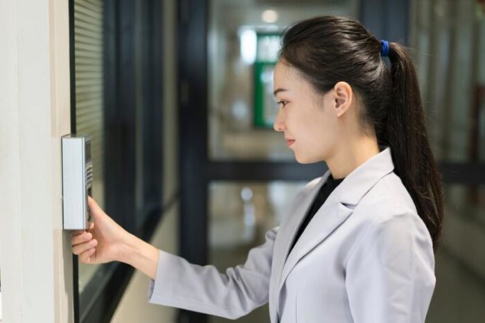 Woman in lab coat pressing button on wall