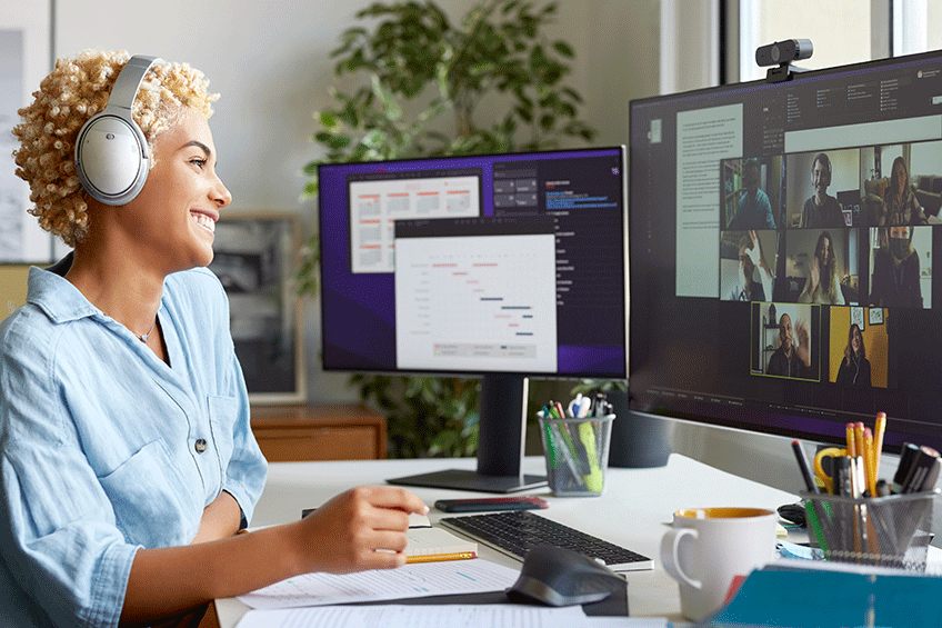 Female wearing headphones on virtual meeting using multiple monitors